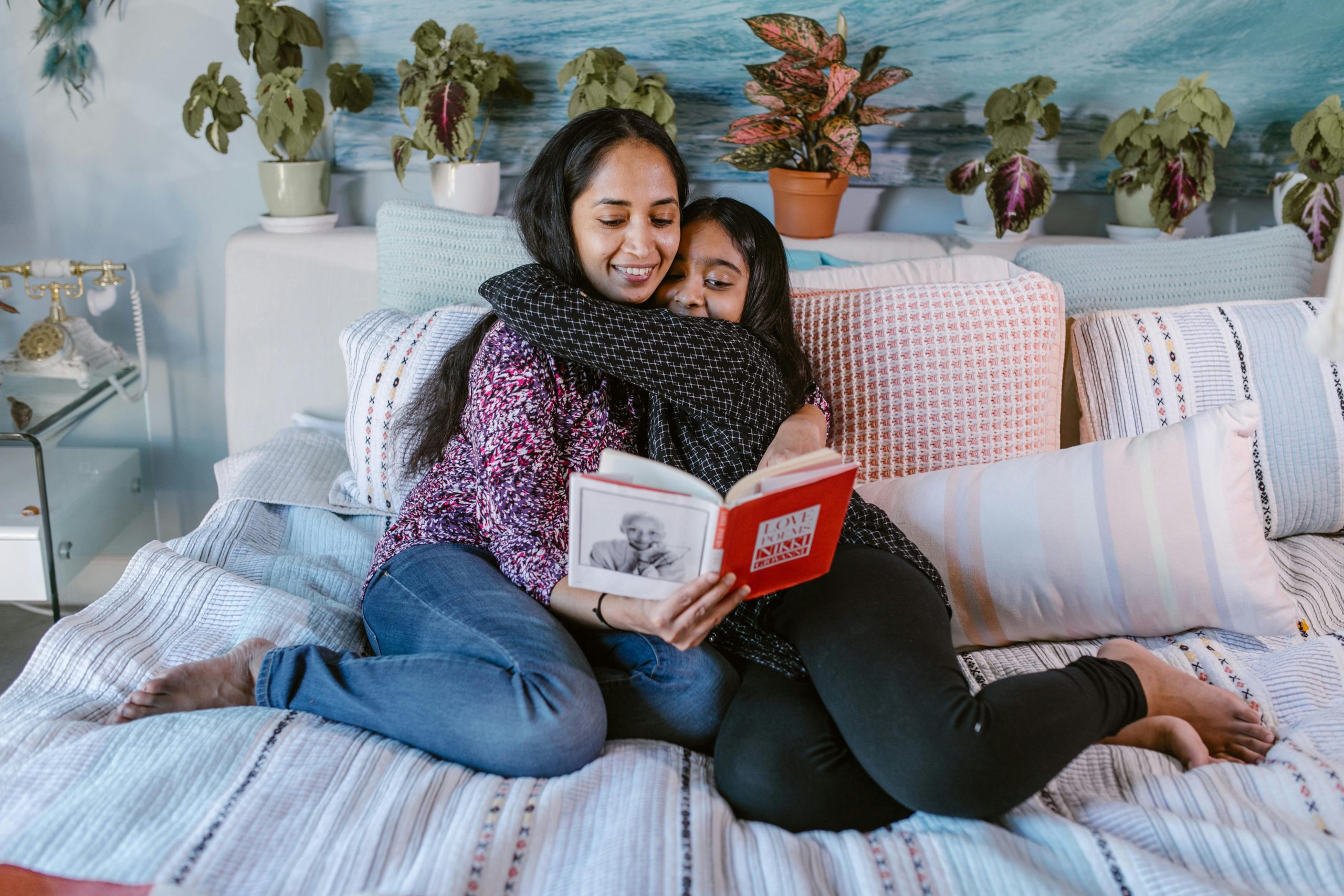 Sisters hugging while reading a book together